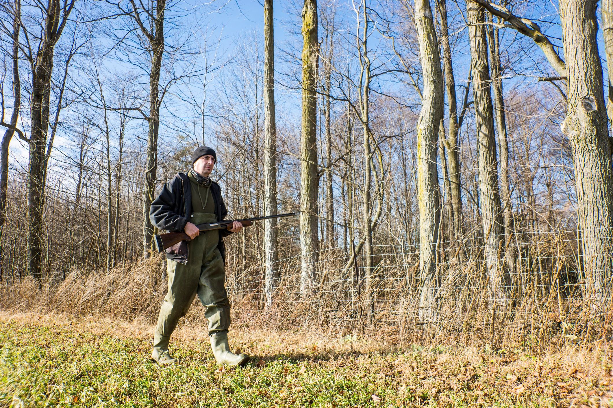 Hunter walking across a field in afternoon light
